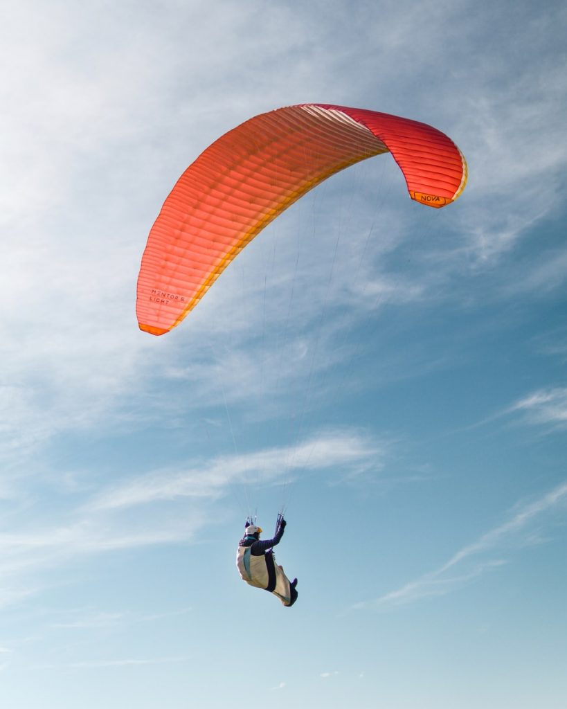 person in orange parachute under blue sky during daytime