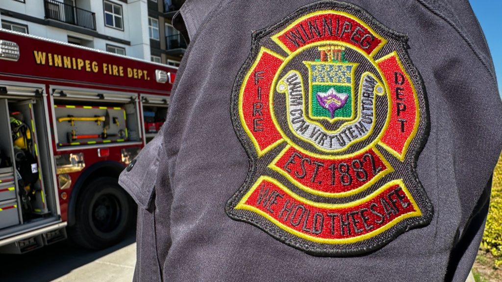 closeup of Winnipeg fire department badge with fire truck in background